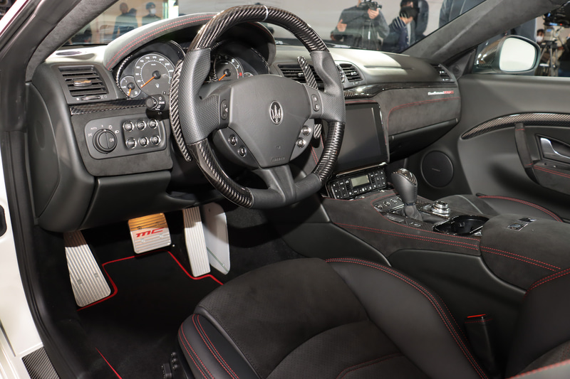 カーボンファイバー製のステアリングホイールやMCデザイン・アルミニウム製スポーツペダル、、レッドステッチなどで車内のスポーティイメージを強調している