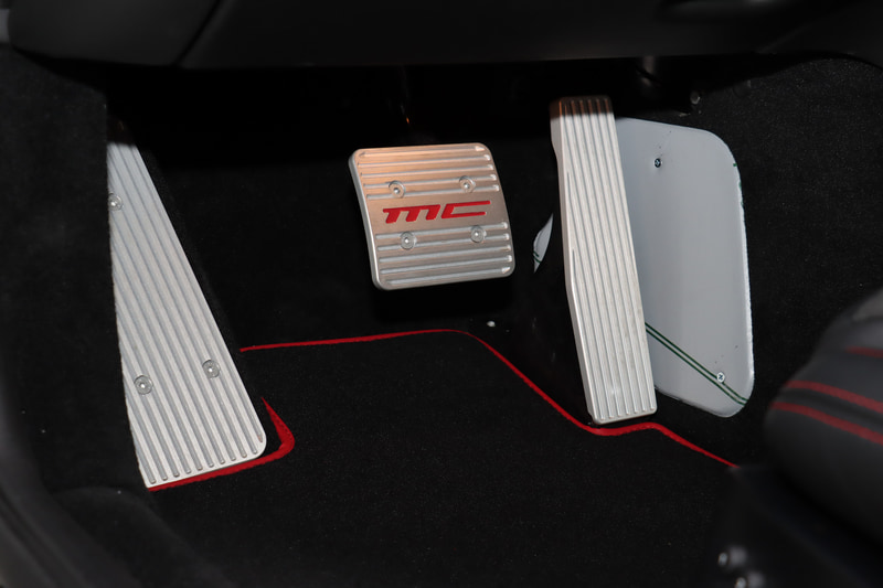 カーボンファイバー製のステアリングホイールやMCデザイン・アルミニウム製スポーツペダル、、レッドステッチなどで車内のスポーティイメージを強調している