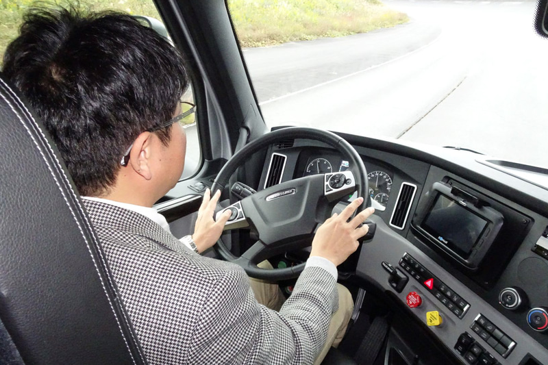 カスケディア（写真左）とアクトロス（写真中、右）によるADA。今回は三菱ふそうのテストコースを使った試乗だったので、公道では許されていない手を放した状態での走行も試してみた。各国各地域の技術指針に則り、手放しが検知されるとほどなくして警報ブザー＆ディスプレイ表示による報知がしっかりと行なわれ、そのまま手放しを続けると60秒しないうちに車線中央維持機能が解除された