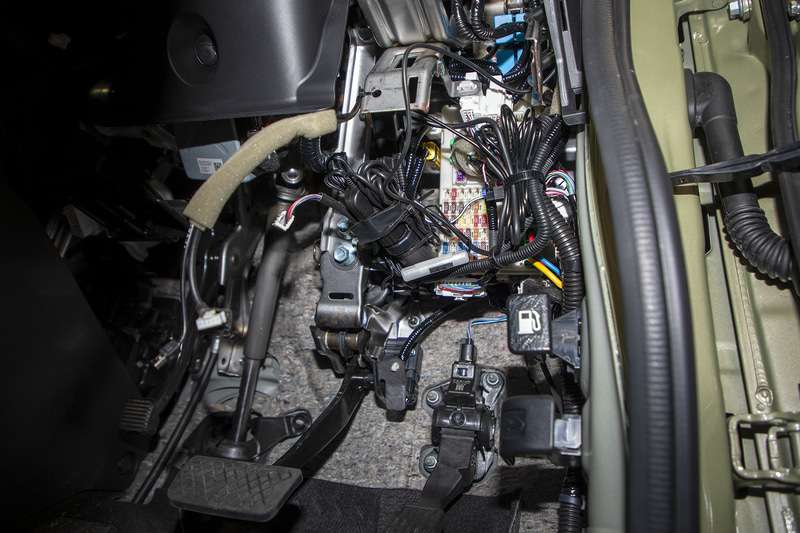 運転席の足下からインパネ下をのぞき込むとヒューズボックスが見えるが、まわりは配線だらけ。しかもヒューズボックスだけに多くのカプラーが刺さっている。見えていても取り外しまでの道のりは遠い