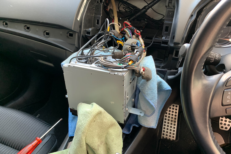 カーナビを抜き出す。このとき他のパネル類に傷をつけないようウエスなどを挟んで養生しておいたほうがベター