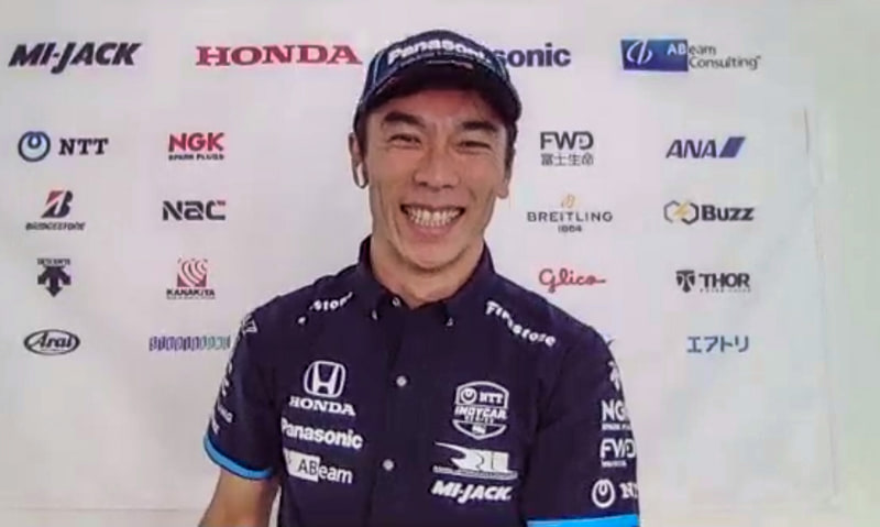 アメリカの自宅でオンラインインタビューに応じる佐藤琢磨選手、スポンサーロゴなどが入っている会見用背景は、日本でデザインをしたデータをアメリカに送り、アメリカでプリントアウトしたものだという。とても今っぽい