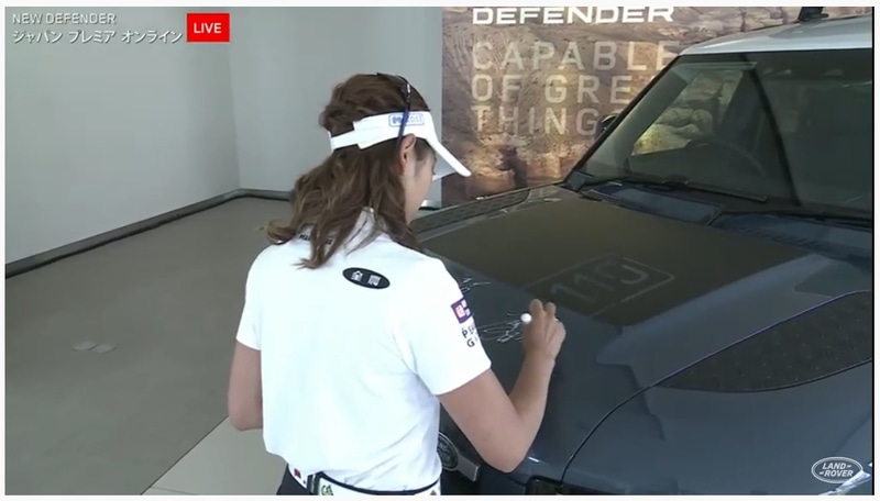 ライブ配信終了後、展示されていた新型ディフェンダーのボンネットにアンバサダーの3人がサインをした