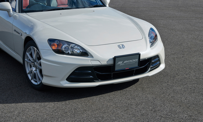 フロントエアロバンパー。フェイスリストをすることでコンセプトである“20年目のマイナーモデルチェンジ”を体現するエアロバンパーとした。コンプリートカーブランドである Modulo X シリーズの開発で培ったノウハウを、このフロントエアロバンパーにも投入。バンパー下面中央部のボックス形状は、張り出したジャッキアップポイントを避けるように強い空気の流れを生み出し、これにより直進性を高める。バンパー下面のサイドには細かいフィンを設けることでホイールハウス内への空気の流れをやさしくし、サスペンションの動きをスムーズにするとともに乗り心地のよさに寄与。バンパーサイドの張り出しはステアリングを30度ほど切った際、タイヤへ直接風が当たることを防ぎ、これによりステアリング操作が軽くなり、より素直な旋回姿勢へ移行してステアリングの切りすぎや揺り戻し防止にもつながるという。S2000にマッチさせ、最新のロー&ワイドを感じさせながらも純正の持つ品格を表現した形状を追求した