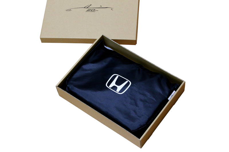 ボディカバー ハーフタイプ。脱着が容易なハーフタイプのボディカバーをリメイクし、従来型のブルーからブラックに変更。展開時はフロントウインドウ部にS2000ロゴを、収納時はホンダの象徴でもあるHマークを入れた。この商品のみ、特別仕様の包装箱を用意、収納用の袋のサイズも収納にあったサイズに変更するといったこだわりを詰めた