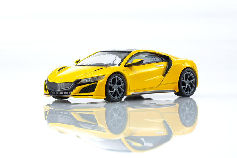 NSXの1/64スケールミニカーは、インディイエローパールIIをベースにしたカラーを採用。ディスプレイ用の台座も付属する