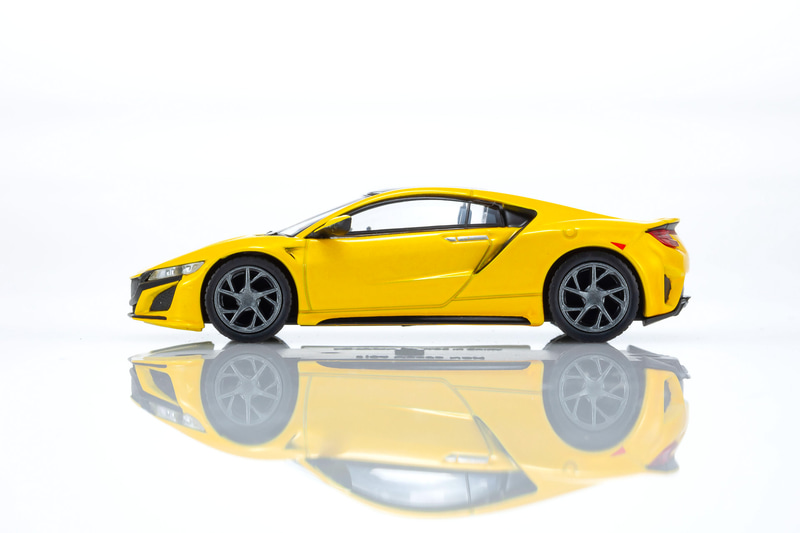 NSXの1/64スケールミニカーは、インディイエローパールIIをベースにしたカラーを採用。ディスプレイ用の台座も付属する