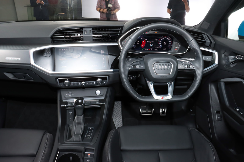 Q3 スポーツバック 35 TDI quattro S lineのインパネ。パドルシフトを備えるフラットボトムのレザーステアリングはS lineモデルに標準装備。ほかの一部グレードにオプション設定される。センターコンソールにフロントグリルを連想させる“オクタゴンモチーフ”を採用。高解像度10.1インチタッチパネルを採用するMMIナビゲーションは「Apple CarPlay」「Android Auto」に対応