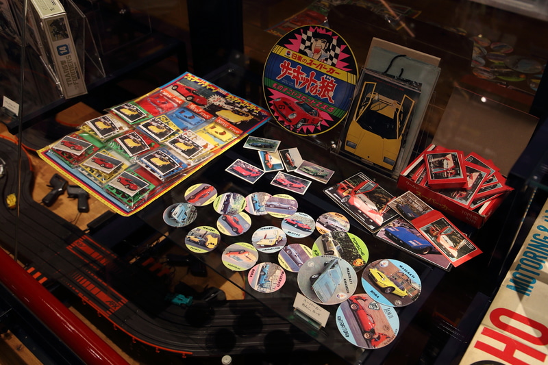 1970～80年代の小学生を直撃したスーパーカーブームに登場した様々なアイテム。その出来具合のバラバラさ加減が当時を思い起こさせる消しゴムや、メンコ、プラモデルなど多数展示しています