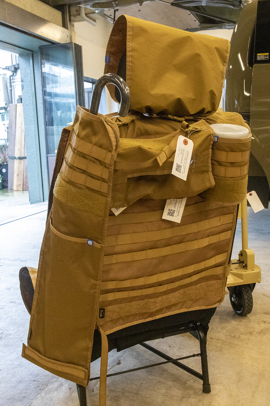 シートバックカバー＋CORDURAシートバックオーガナイザーの組み合わせ。シートバックオーガナイザーはミリタリーアイテムで使われるモールシステムを装備したもので、システムポーチを自由に配置したり、カラビナやフックなどで小物をシートバックに吊すこともできる。シートバックオーガナイザーの価格は8800円。そのほかアンブレラケース、ティッシュカバー、ウエットティッシュカバーをモールシステムで取り付けている