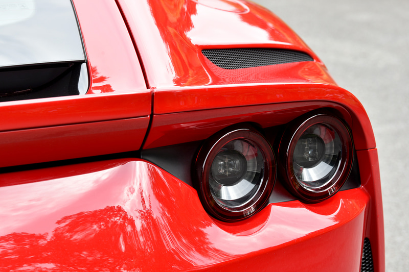 外観ではハイ・テールの2ボックススタイルが1969年の「365GTB4」を想起させ、フルLEDヘッドライトは隆起するフロントホイールアーチを含めてボンネットのエアインテークと一体でデザインすることでフロントの力強さを強調。リアまわりでは、フェラーリ伝統の4灯丸型テールランプが水平方向に広がるフォルムを強調し、スポイラーとキャビンを低く見せる視覚的効果によってワイド＆ローを演出しているという。エキゾーストパイプはチタニウム製