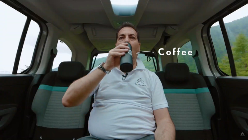 ベルランゴのリアシーリングボックスからタンブラーを取り出してコーヒーを飲むGroupe PSA Japan株式会社 代表取締役社長 アンジェロ・シモーネ氏