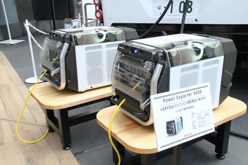 チャージングステーションから充電を行なっているのが可搬型外部給電気「Power Exporter 9000」。大型電気製品からパソコンなどの精密機器まで、さまざまな電気機器に最大9kVAまでの電力を供給できる