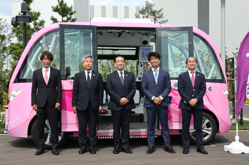 自律走行するバスの「NAVYA ARMA」の前に立つ各社の代表。左から日本交通株式会社 常務執行役員 佐藤真吾氏、鹿島建設株式会社 執行役員開発事業本部長 塚口孝彦氏、羽田みらい開発株式会社 代表取締役社長 山口皓章氏、BOLDLY株式会社 代表取締役社長兼CEO 佐治友基氏、株式会社マクニカ 代表取締役社長 原一将氏