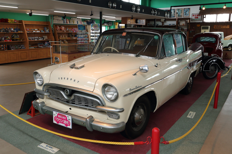 館内には昭和34年式の初代トヨペット クラウン。入り口の同型モデルとの細部がずいぶん違います。こちらにはエンジン始動のためのクランク棒の差し込み口が見えます