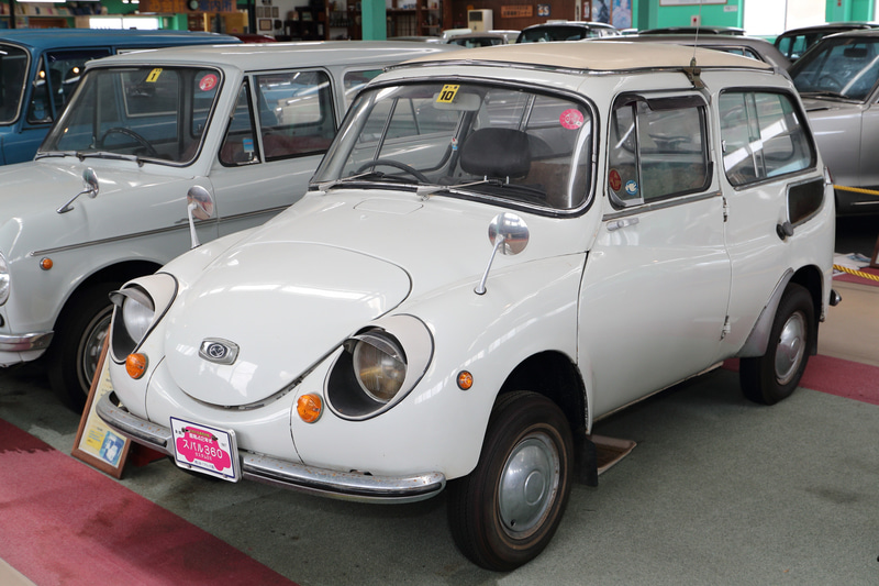 昭和42年式のスバル360 カスタムDXは、柔らかなボディラインを持ちながらほぼ垂直に近い角度のテールゲートを備えた商用モデルです