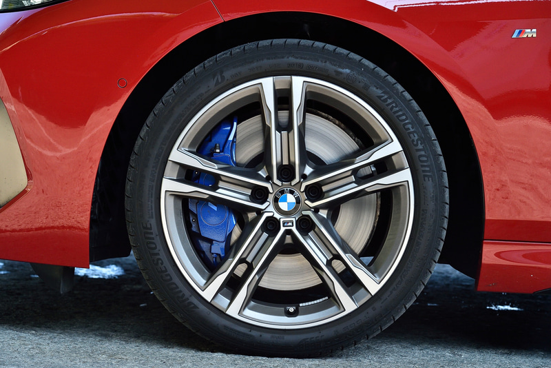 M235i xDriveではメッシュデザインのキドニーグリルをはじめ、専用の台形型デュアルエキゾーストテールパイプを採用。キドニーグリルやエアインテークトリム、ミラーキャップなどはセリウム・グレーで統一され、よりアグレッシブな外観に仕上げられた。足下はダブルスポークの18インチホイールにブリヂストンのランフラットタイヤ「TURANZA T005」（225/40R18）の組み合わせ