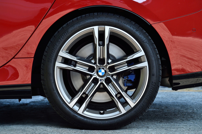 M235i xDriveではメッシュデザインのキドニーグリルをはじめ、専用の台形型デュアルエキゾーストテールパイプを採用。キドニーグリルやエアインテークトリム、ミラーキャップなどはセリウム・グレーで統一され、よりアグレッシブな外観に仕上げられた。足下はダブルスポークの18インチホイールにブリヂストンのランフラットタイヤ「TURANZA T005」（225/40R18）の組み合わせ