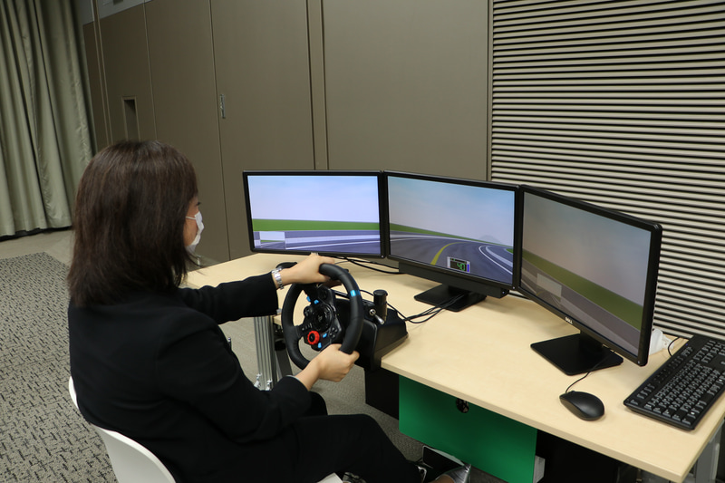 後遺症がどのくらい残っているのかを検査できるリハビリシステム。ステアリング操作を行ないつつ、画面上に緑の点が出たら素早くアクセルを戻して再度踏み込む動作を3分半ほど繰り返す。3つの画面はさらに9つに分割されていて、どこが見え難い、見えていないなどが容易に調べられる。同時に反応速度（表の水色部分の数値）やステアリング操作の安定性（赤いグラフ）も可視化され、運転再開に適しているかの判断材料のひとつになる。2枚の表を見比べると違いがよく分かる