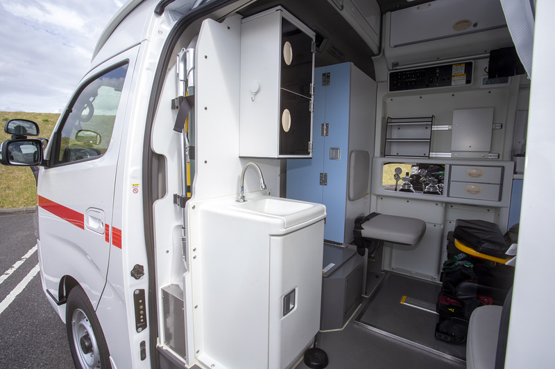 運転席とは通路で繋がっていて収納スペースも多い。右側側に備え付けてある医療用酸素ボンベへのアクセス窓もあった