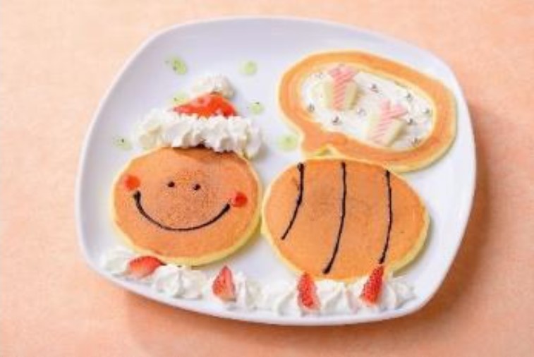 ぶんぶんのパンケーキやさんでは「ぶんぶんサンタのプレゼントパンケーキ」（700円）を12月25日限定で販売。いちごジャムと生クリームで彩ったサンタ帽子をかぶってプレゼントを運ぶ「ぶんぶん」を描いたパンケーキで、大きな袋の中にはプレゼントをかたどったホワイトチョコレートがトッピングされている