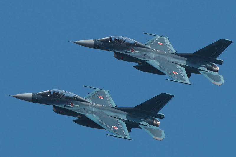 2機編隊でツインリンクもてぎ上空を飛ぶ航空自衛隊「F-2B戦闘機」。機体記号23-8113と33-8119が松島基地から飛来した