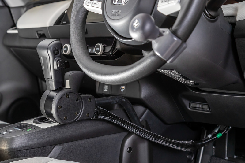 コントロールレバーから前方に伸びている黒いチューブの中に入っているワイヤで、アクセルとブレーキを操作する