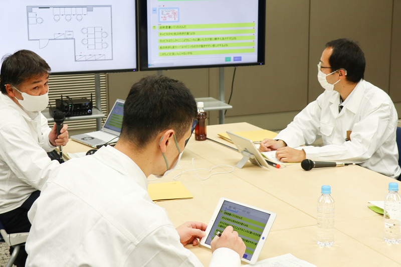 手前側の従業員がタッチパネルで手書き入力中。手書き文字を使った筆談も交えてコミュニケーションができる