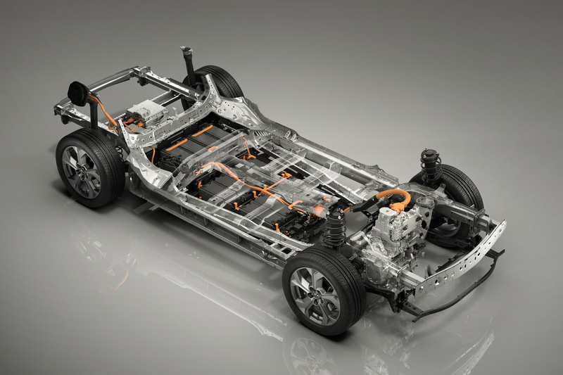 e-SKYACTIVのシステムはモーター、高電圧バッテリー、インバーター、DC-DCコンバーター、AC普通充電器などの高電圧部品で構成。バッテリーの直流電流はインバーターで交流に変換してモーターを駆動させ、DC-DCコンバーターで降圧させることで12V系の各種補機類に電力を供給する。モーター、インバーター、DC-DCコンバーター、ジャンクションボックスは高電圧ユニットとして一体化し、車両前部に搭載。フロア下に搭載される高電圧バッテリーは、電池モジュールの高密度搭載や、薄型のバスバー配線を採用して最小化した高電圧部品間の配線設計、薄型構造の冷媒冷却方式の採用により、バッテリーケースの高さを抑制。室内空間への影響を最小限に抑え、快適な居住性を確保した充電口は普通充電・急速充電ポートをセットにして右リアフェンダー部に、AC普通充電器はラゲッジルームに配置。車両との協調制御による電力消費の削減などによって、駆動に活用できるエネルギーを最大化している