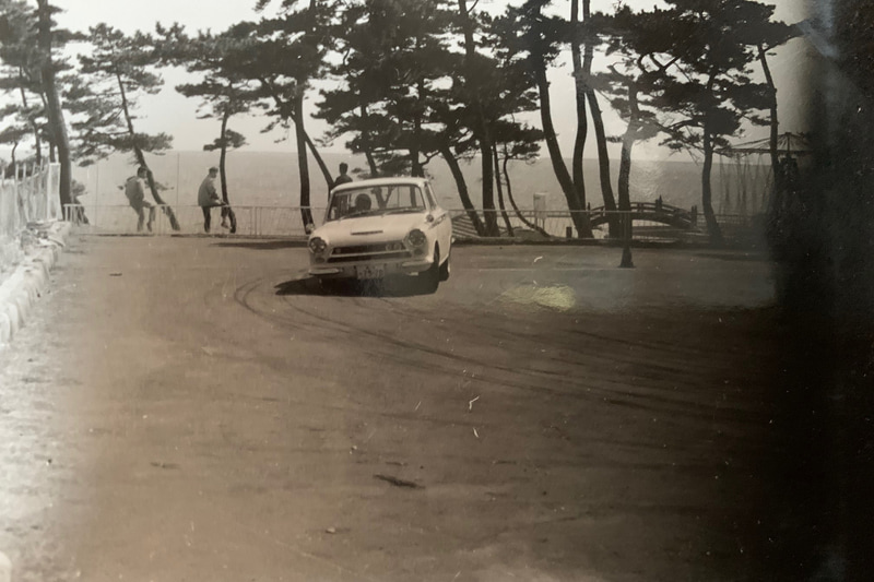 大磯ロングビーチのジムカーナ。まだジムカーナ専用車両は少なく、普段使っているスポーツカーで楽しんでいる人が多かった。元祖「羊の皮を被った狼」コルチナ・ロータス。フォードの大衆車、コルチナをロータスがエンジンを乗せ換えて足も変えたセダン。グリーンのサイドストライプが目印です