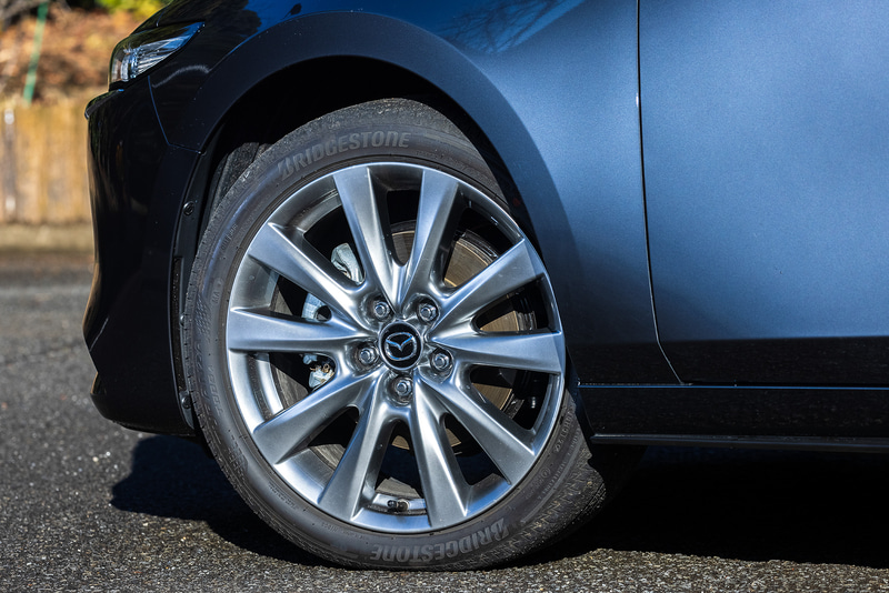 今回試乗したのは2020年11月に商品改良した「MAZDA3」。写真はセダンの「X L Package」（2WD/338万463円）で、ボディサイズは4660×1795×1445mm（全長×全幅×全高）、ホイールベースは2725mm。今回の改良で外観ではフロントフェンダー部に「SKYACTIV-X」バッヂを、リア部に「e-SKYACTIV X」バッヂを装備。足下は18インチホイールにブリヂストン「TURANZA T005A」（215/45R18）を組み合わせる