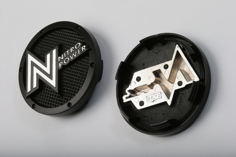 ハブキャップに入っているロゴは一体成型ではない。立体感の強いデザインのホイールに合わせて、立体感を出すための文字の部分は別パーツとして、それをキャップのベースにはめ込んでいる。さらにベース部分もフラットでなく細かい凹凸を付けるという非常に凝った作りになっている