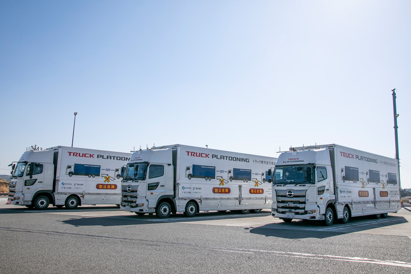 3台の大型トラックはサイドパネルに実証実験中であることを示す文字やイラストを備えて周辺車両に注意喚起