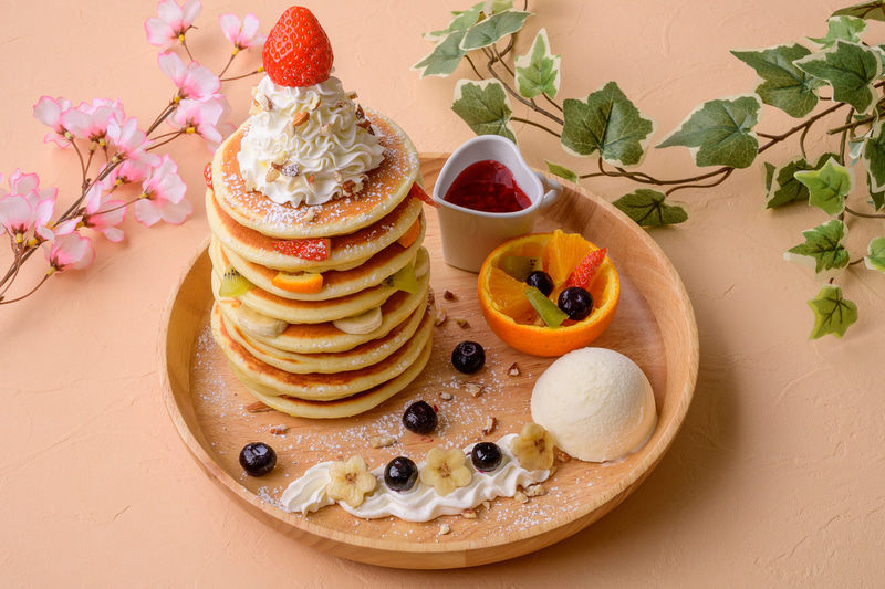 ポタジェンヌラリー対象メニュー「フルーツ収穫ポタジェンヌタワーパンケーキ」（1800円）。販売店舗はぶんぶんのパンケーキやさん。ポタジェンヌ外観をイメージした8枚のパンケーキとフルーツを重ねたタワーパンケーキ。オレンジのかごには収穫フルーツがたくさん入っている