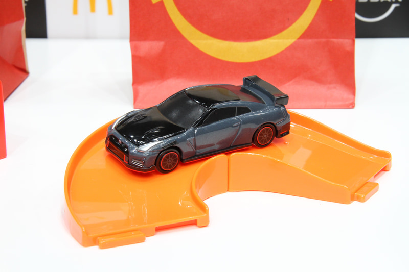 ハッピーセットで用意されるひみつのおもちゃの「日産 GT-R NISMO 2022年モデル マクドナルド仕様“ゴールド”、通常のおもちゃとなるNISMOステルスグレーを模した「日産 GT-R NISMO 2022年モデル」