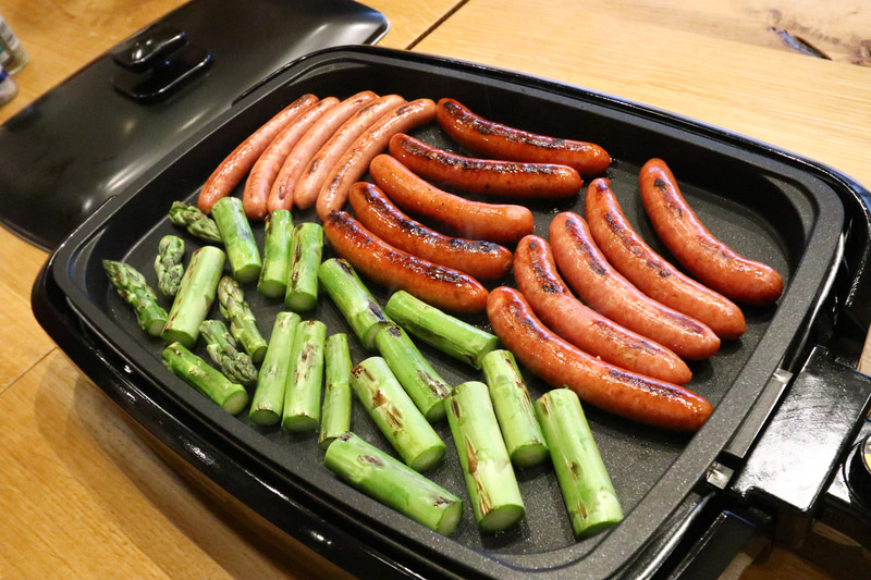 朝食もホットプレートでソーセージとアスパラを焼く