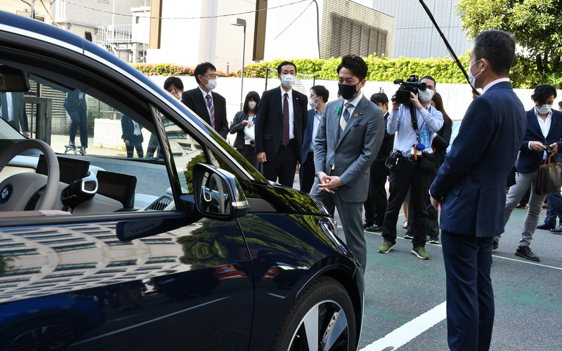 記念写真撮影後、各社担当者と電動化車両について会話する小泉大臣