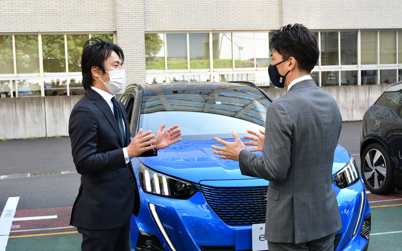 記念写真撮影後、各社担当者と電動化車両について会話する小泉大臣