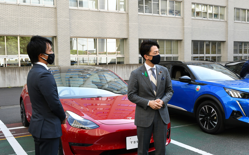 記念写真撮影後、各社担当者と電動化車両について会話する小泉大臣