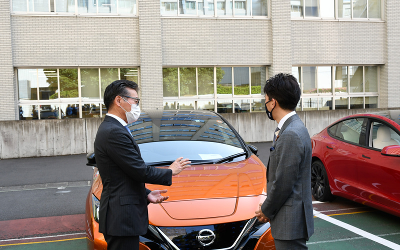 記念写真撮影後、各社担当者と電動化車両について会話する小泉大臣