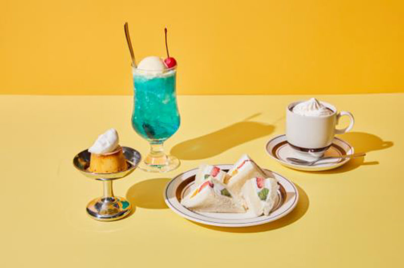 メルセデスイーキューカフェのメニュー。メロンソーダ（650円）：透き通るブルーにさくらんぼが映える甘さがスッキリとした味わい。フルーツサンド（800円）：たっぷりのクリームに3種のフルーツをはさんで。プリン(450円）：少し固めでほろ苦い甘さにホイップクリームをトッピング（※東京のみ）。ウィンナーコーヒー（450円）：苦みとコクのあるコーヒーに生クリームを添えて。メロンソーダ＋プリンセット（1000円：※東京のみ）、ウィンナーコーヒー＋フルーツサンド（1100円※大阪のみ）