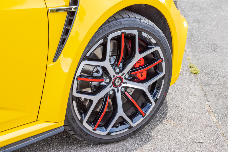 「メガーヌ R.S. トロフィー MT」。ボディカラーはメガーヌ R.S. トロフィー専用色の「ジョン シリウスM」。フロントバンパーのナンバープレート上部に「TROPHYデカール」を装着するほか、19インチアロイホイールが赤いラインが入った専用の“TRIOHY”となる