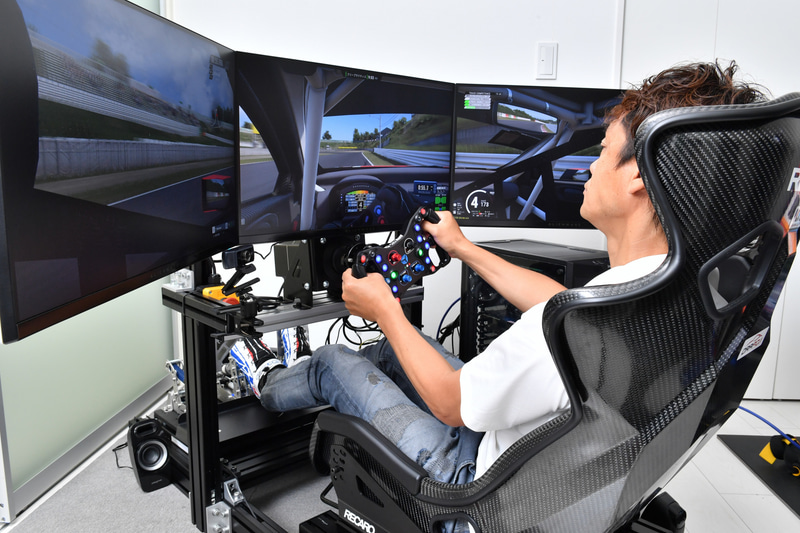 レーシングシミュレータのコクピットに納まる脇阪寿一氏