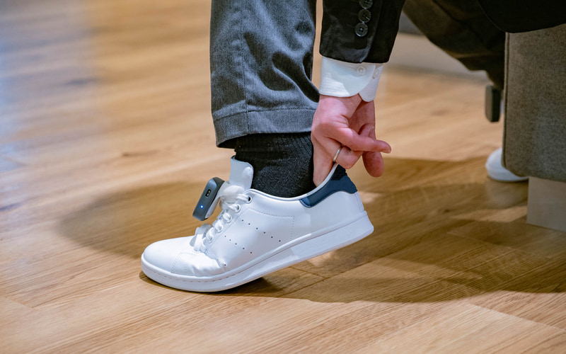 「あしらせ」の立体型のモーションセンサー付き振動デバイスを靴に取り付け、スマートフォンアプリを連動させてナビゲーションを行なう仕組み。振動デバイスを装着したまま、靴の脱ぎ履きもできる