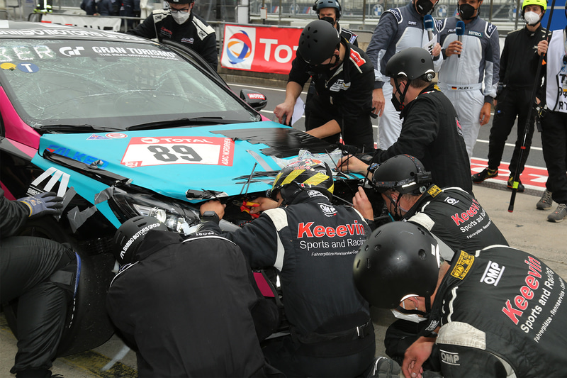 クラッシュしてボンネットが開いたままピットに戻ったマシン。あの手この手で応急処置をする