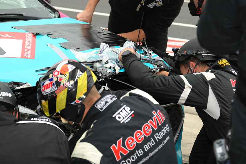 クラッシュしてボンネットが開いたままピットに戻ったマシン。あの手この手で応急処置をする