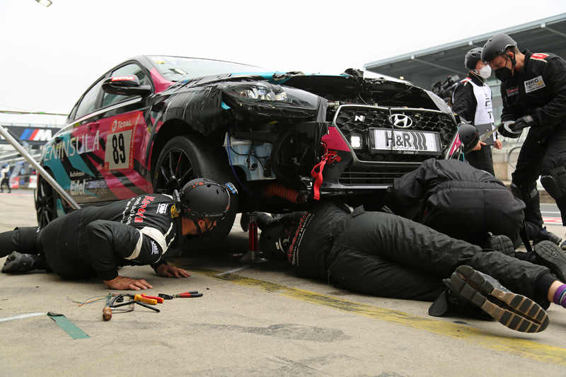 クラッシュしてボンネットが開いたままピットに戻ったマシン。あの手この手で応急処置をする