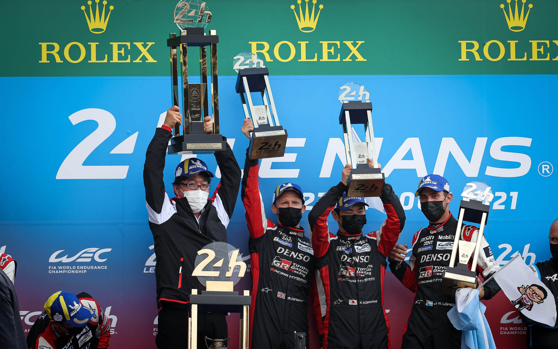 優勝を喜ぶ7号車のメンバー（右から、ホセ・マリア・ロペス選手、小林可夢偉選手、マイク・コンウェイ選手）とTOYOTA GAZOO Racing WEC チーム代表 村田久武氏（左）。モリゾウくんの旗もうれしそう
