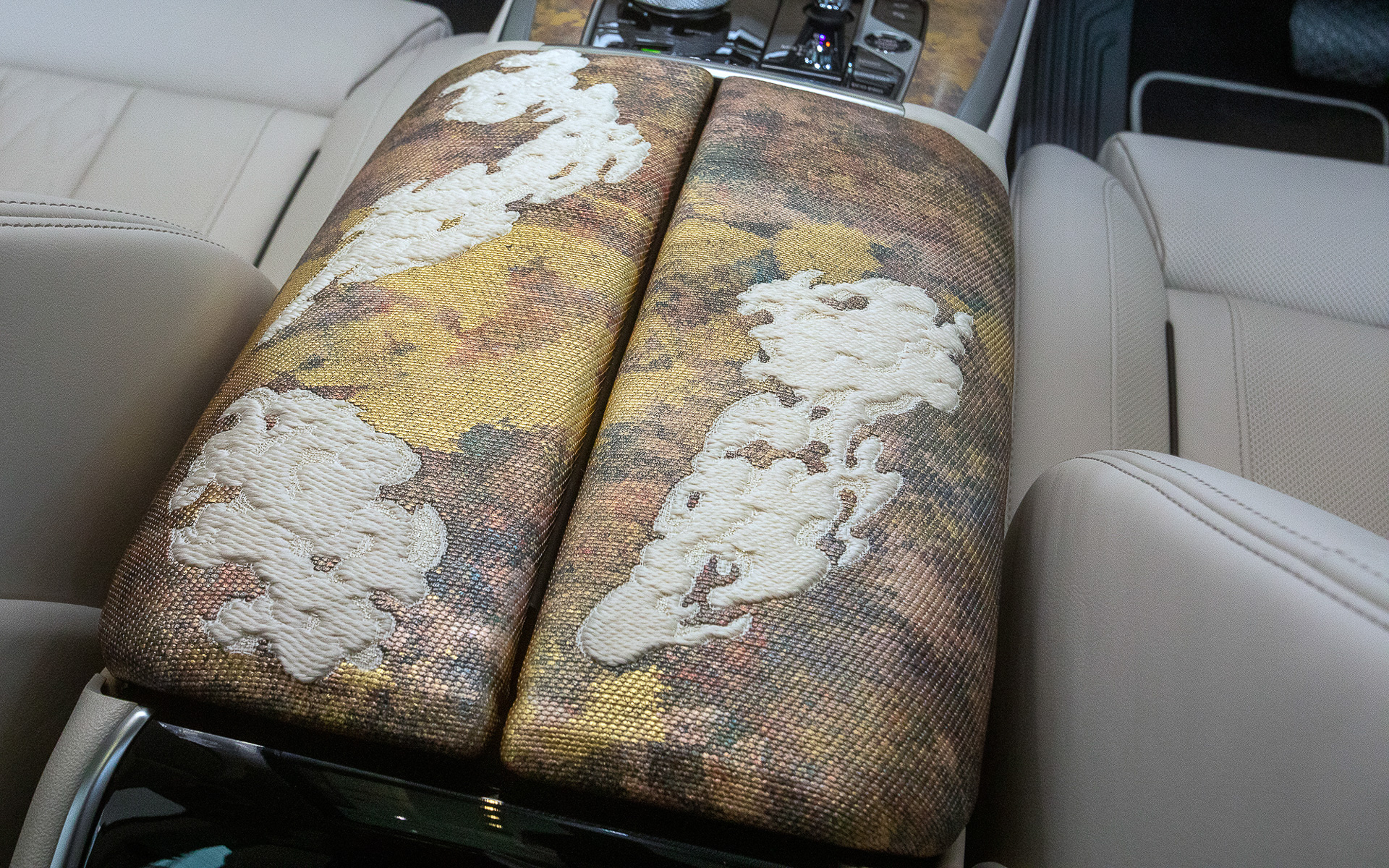 フロントセンターアームレスト。室内に使用する素材ということで難燃性があるメリノ・レザーに泊装飾したあと、細かく裁断してそれを絹の経糸に織り込んでいる。白い部分は卿雲（けいうん）をイメージした立体模様の織りとなる