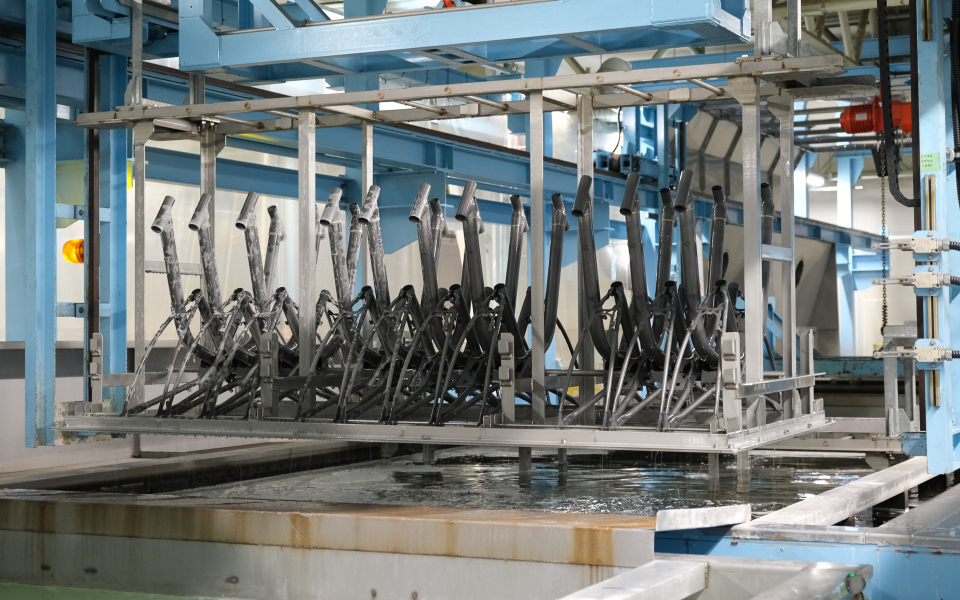 並べたフレームを薬液に沈めるディップ方式の採用により、ムラのない均一な皮膜品質と量産性を両立